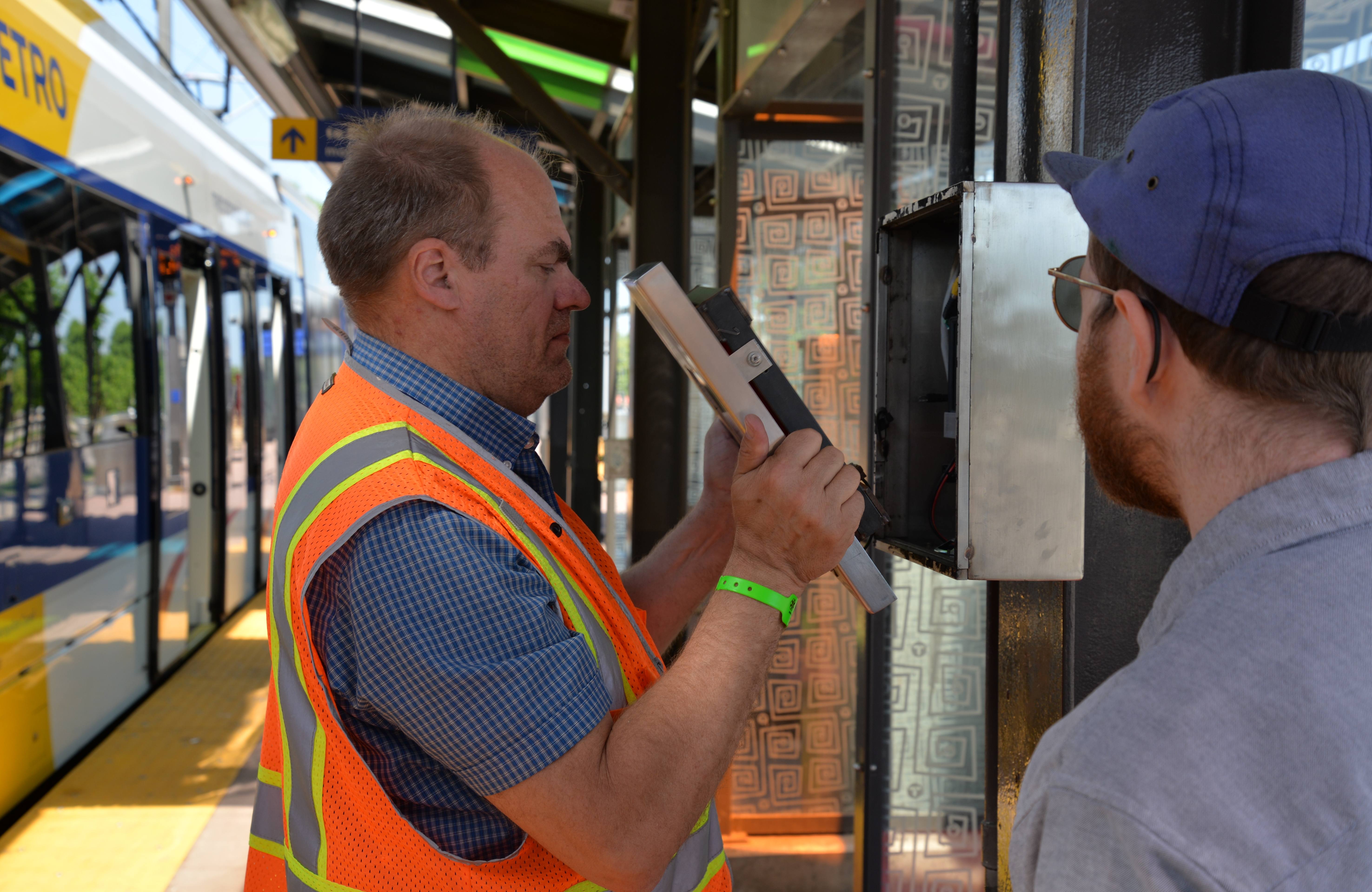Public Art Administrator Mark Granlund and Max Hoaglund, an independent technologist, finish repairs to a box holding a video player at the METRO Blue Line’s 46th Street Station. Public Art Administrator Mark Granlund and Max Hoaglund, an independent technologist, finish repairs to a box holding a video player at the METRO Blue Line’s 46th Street Station.